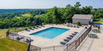 a swimming pool with chairs around it in front of a house